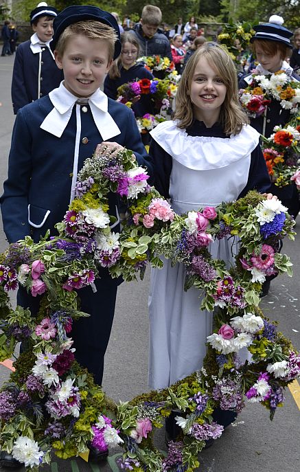 Children carrying star-shaped floral arrangements head the procession of flowers. 